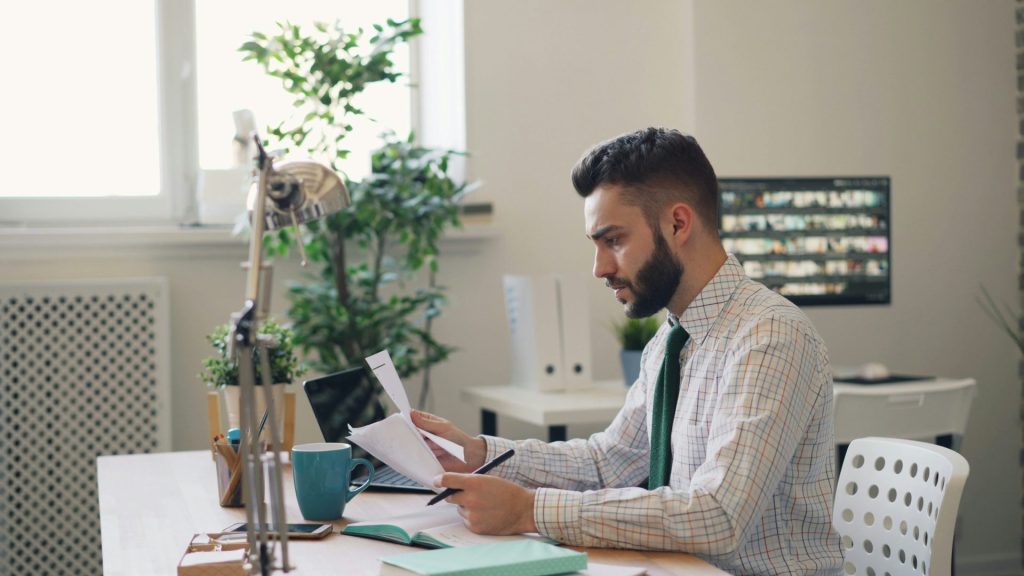 Hombre de camisa y corbata en una oficina mirando documentos